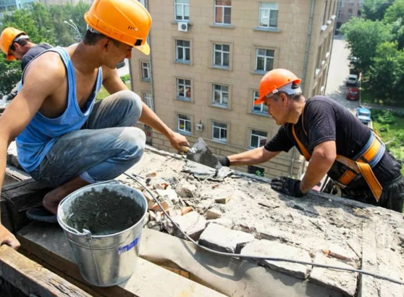 Строители ремонтируют крышу многоэтажки
